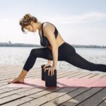 Woman practicing advanced yoga by the water